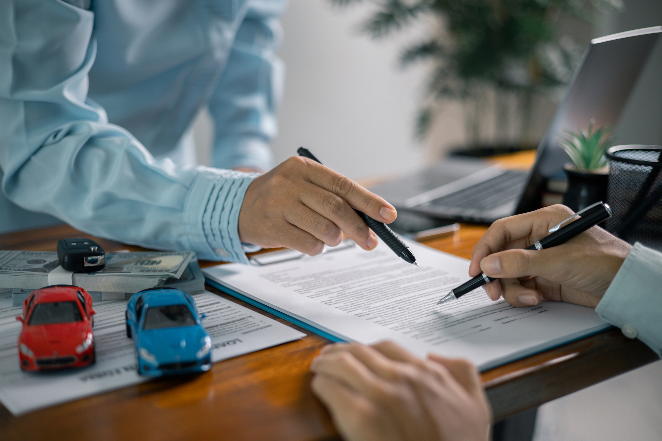 Dealership staff reviewing vehicle purchase contract with customer at desk
