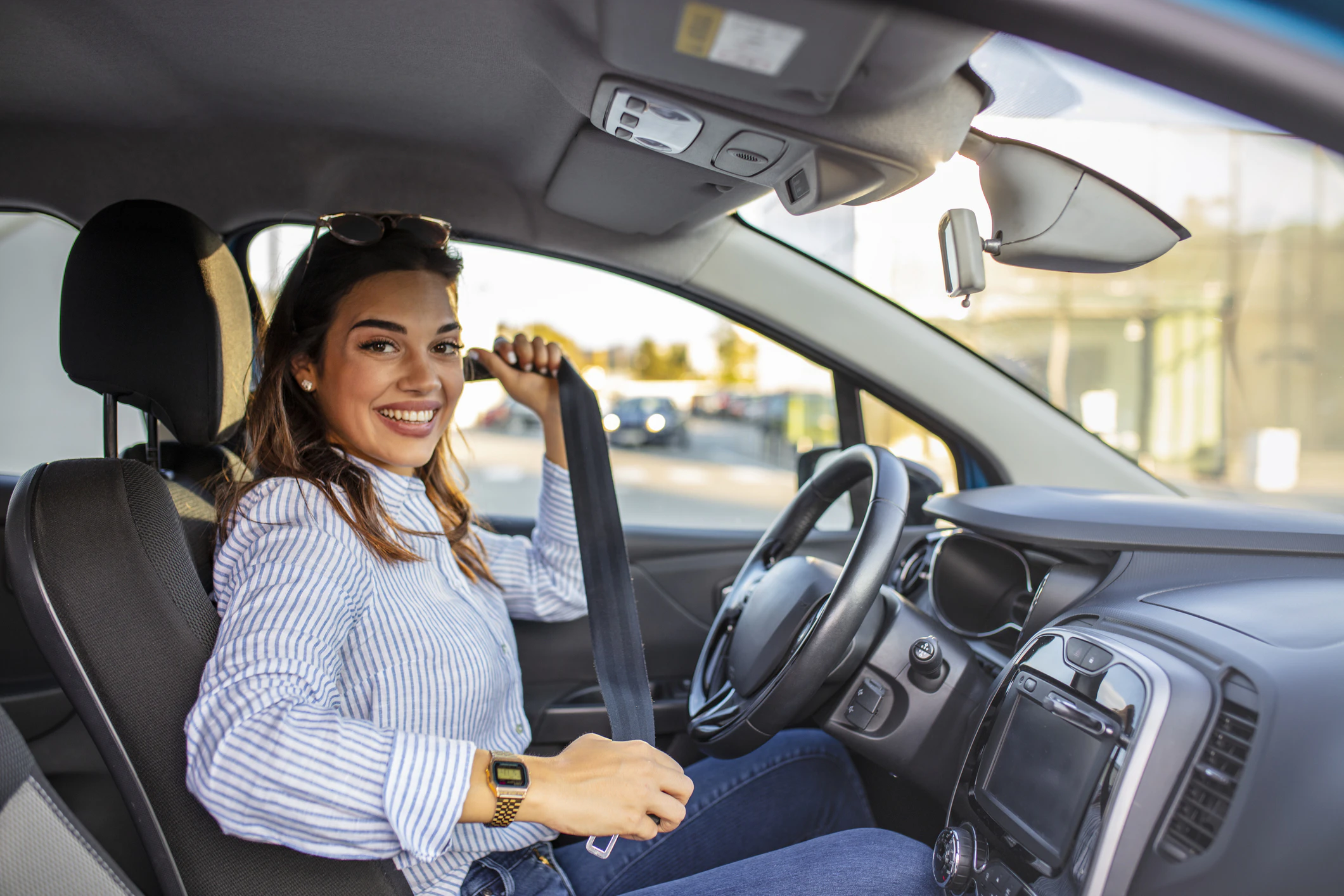 Smiling woman buckling her seatbelt in the driver’s seat of an SUV.