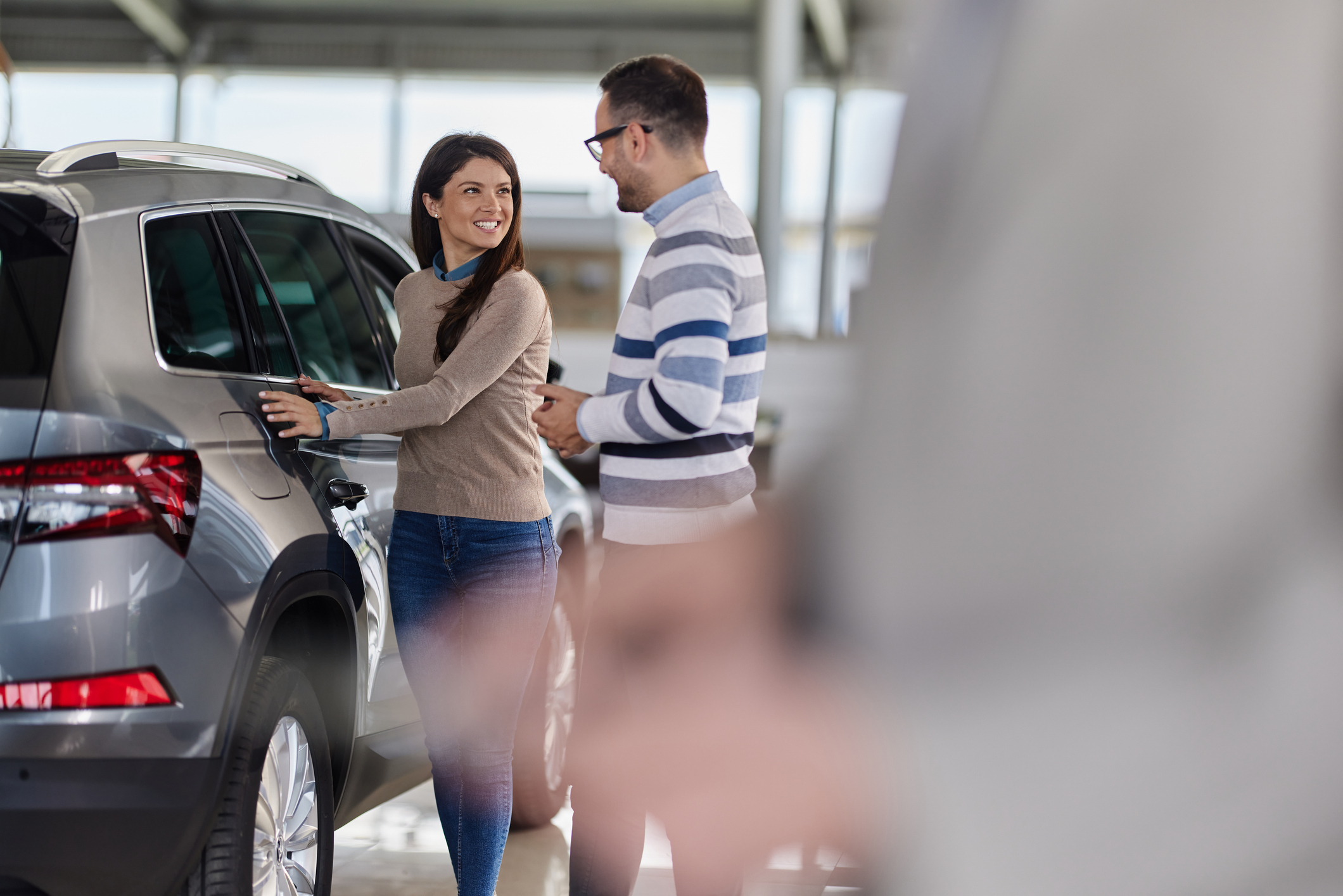 Couple looking at an SUV with a dealership salesperson