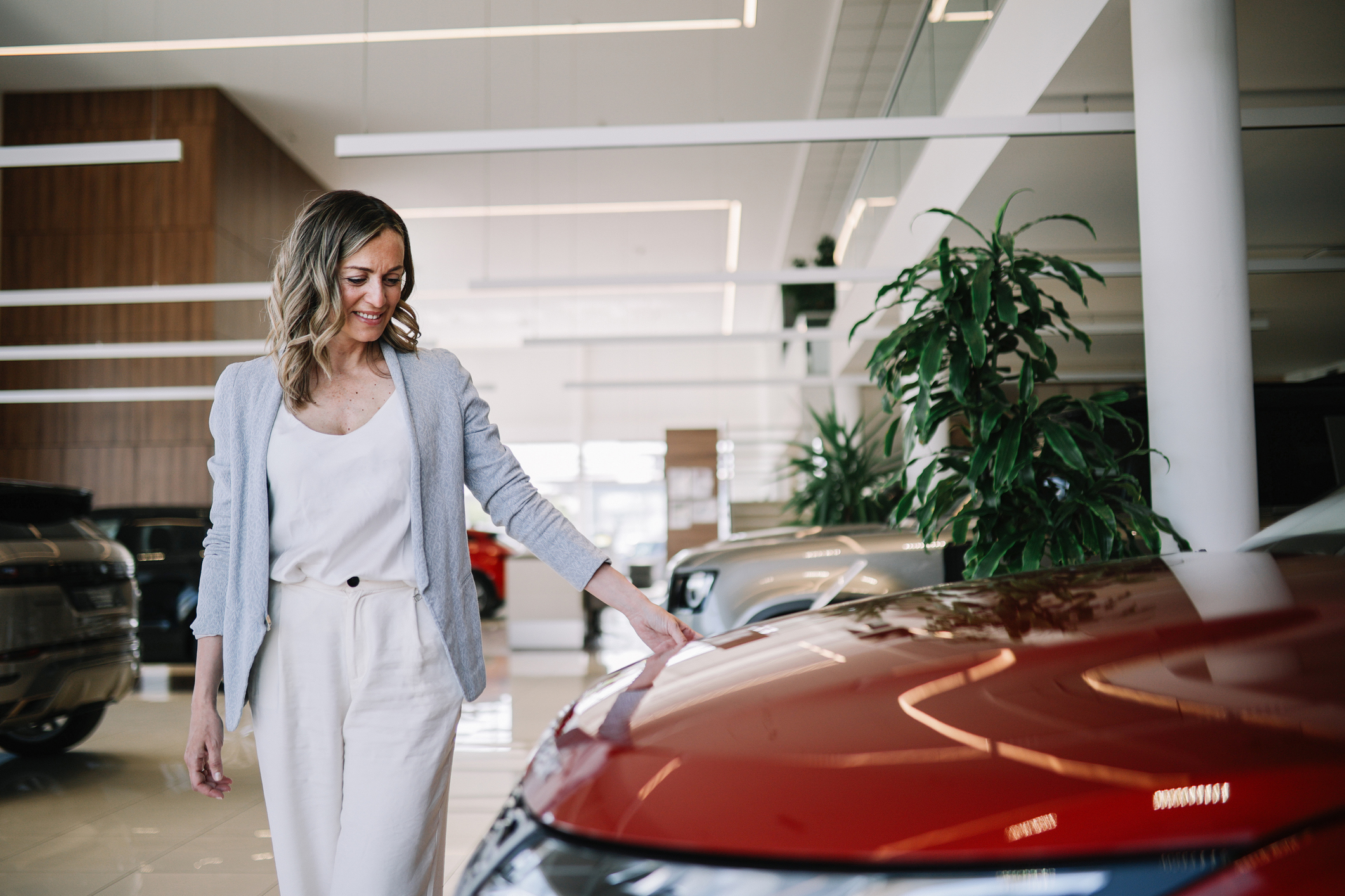 Customer examining red vehicle in modern dealership showroom