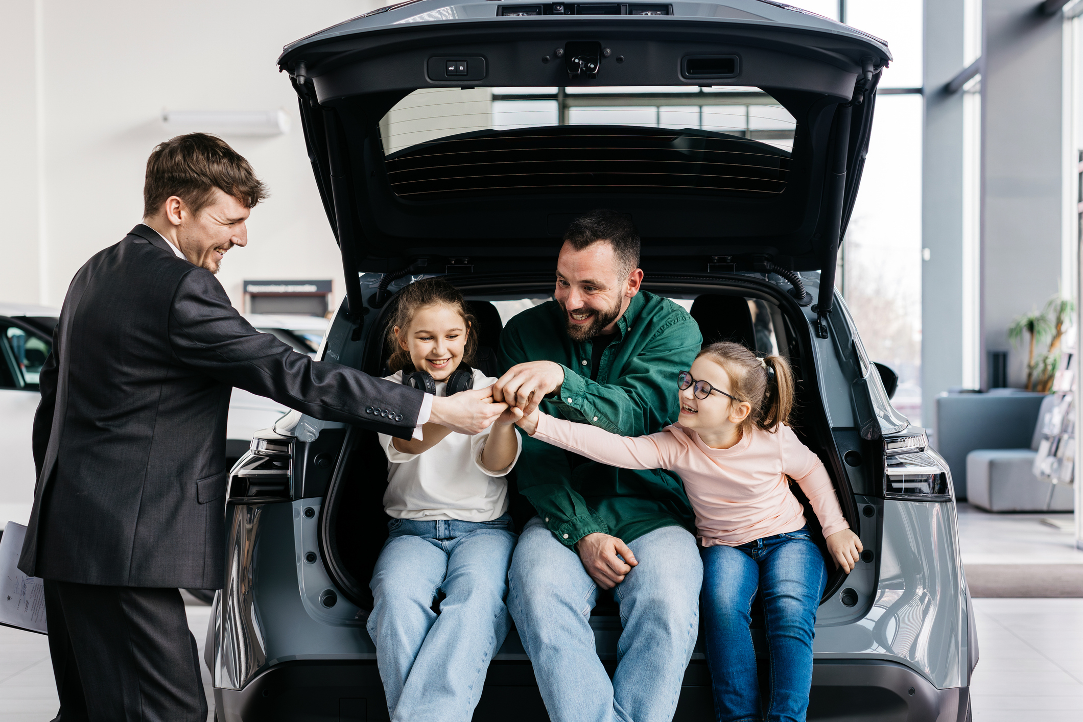 Family sitting in the back of an SUV with a dealership salesperson