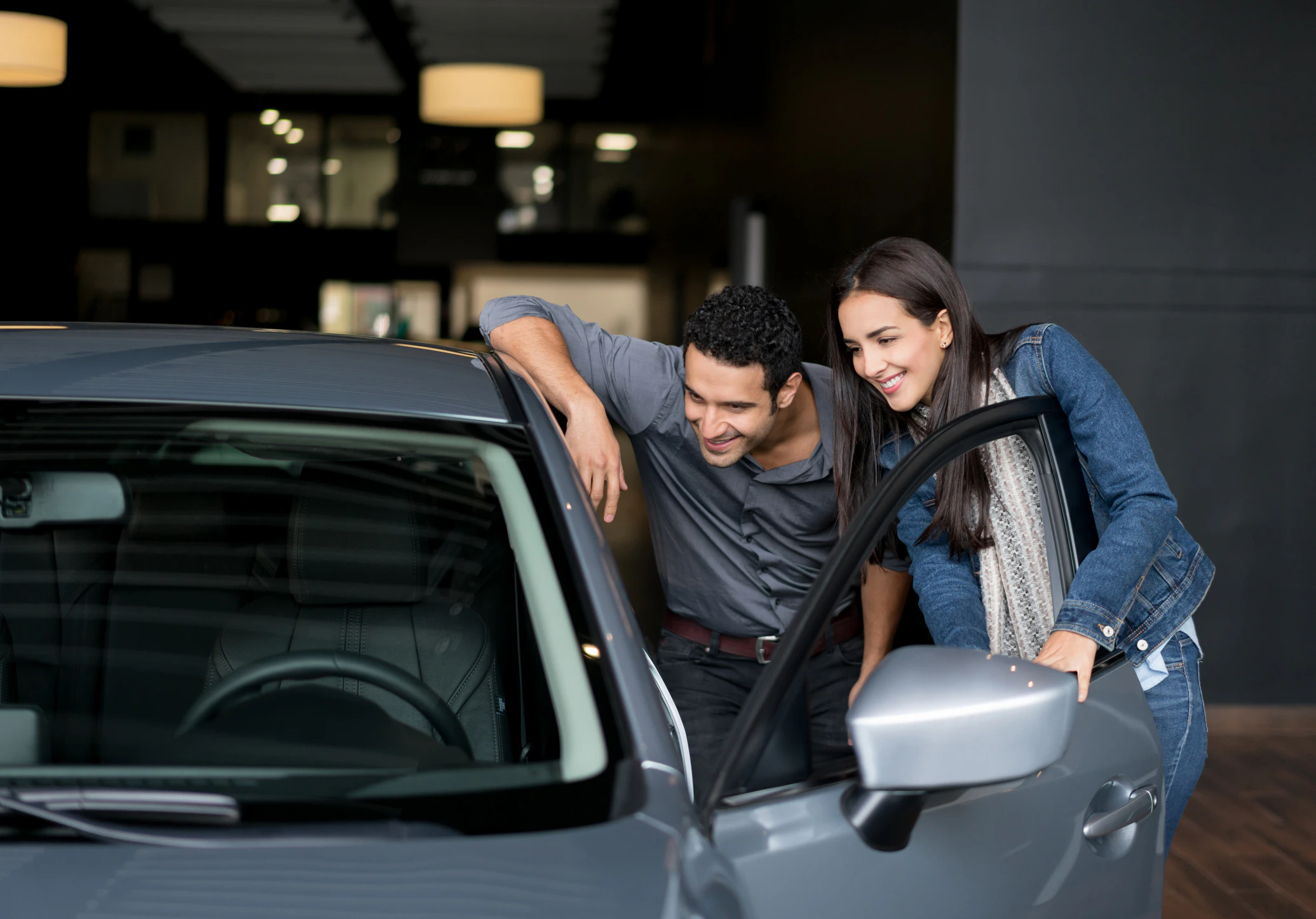 Couple looking inside a car at a dealership