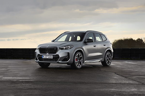 Silver BMW X1 SUV parked on pavement with overcast sky