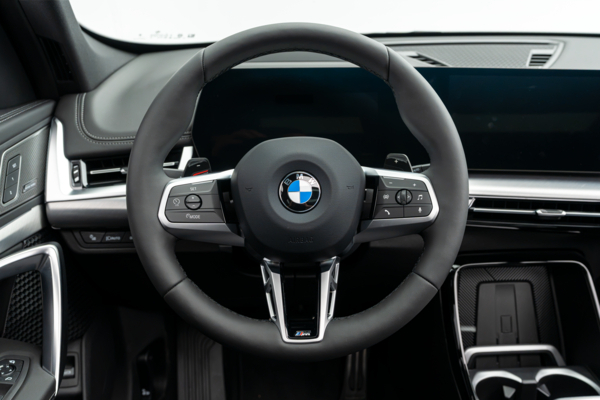 BBMW X1 interior close-up featuring the leather-wrapped BMW steering wheel, dashboard and centre console.