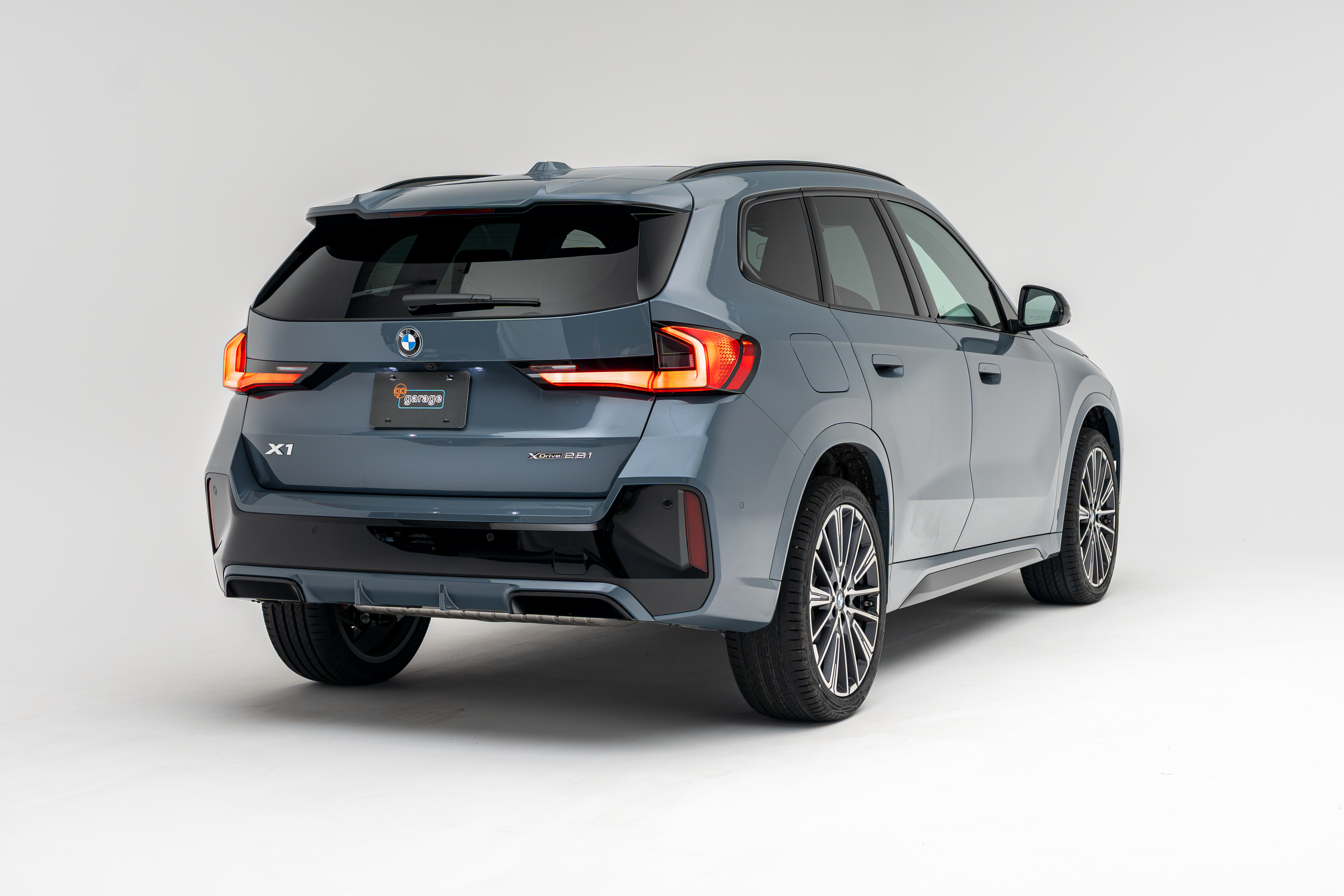 Rear three-quarter view of a grey 2026 BMW X1 xDrive28i SUV on a white studio background.