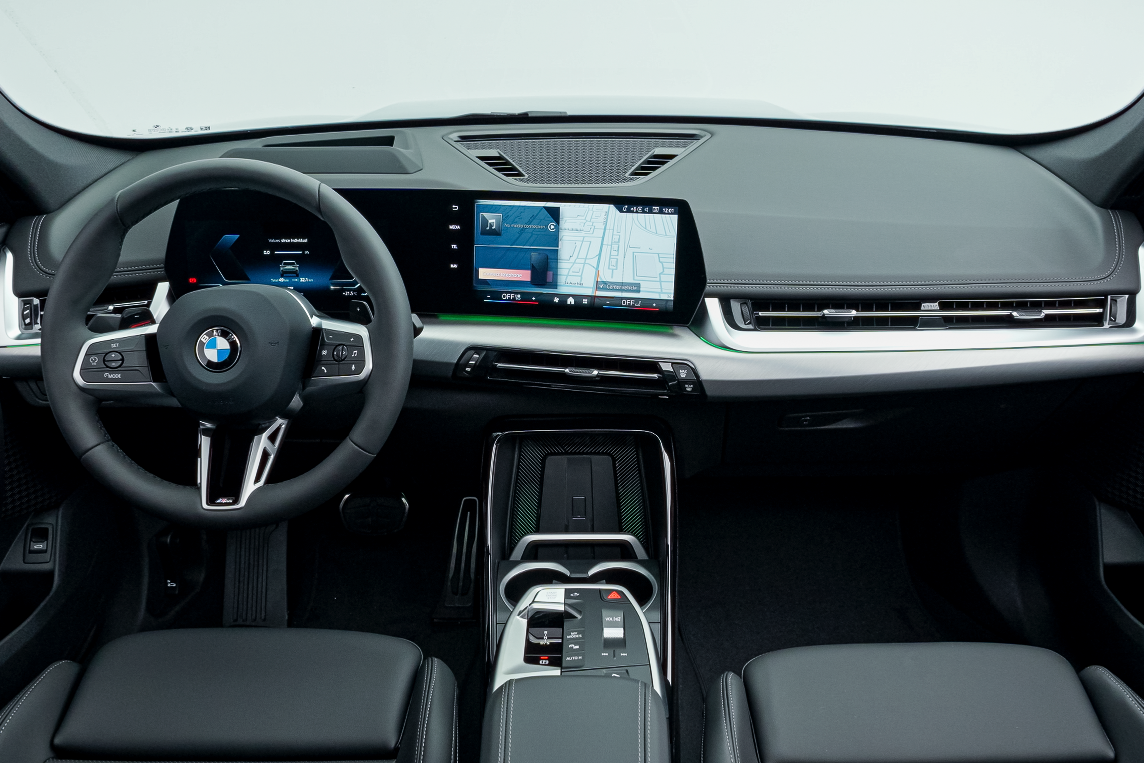 BMW X1 interior featuring a digital instrument display, centre touchscreen, steering wheel, centre console and black leather seats.