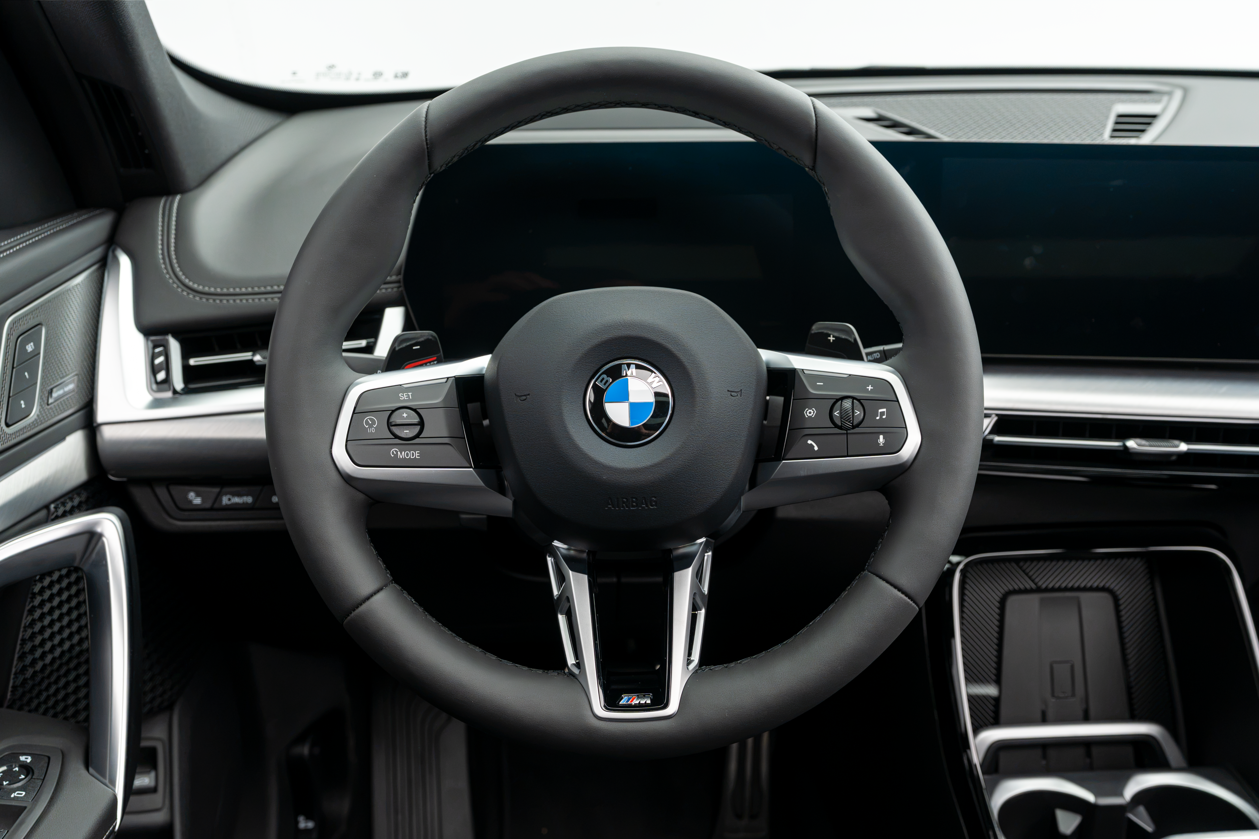 BBMW X1 interior close-up featuring the leather-wrapped BMW steering wheel, dashboard and centre console.