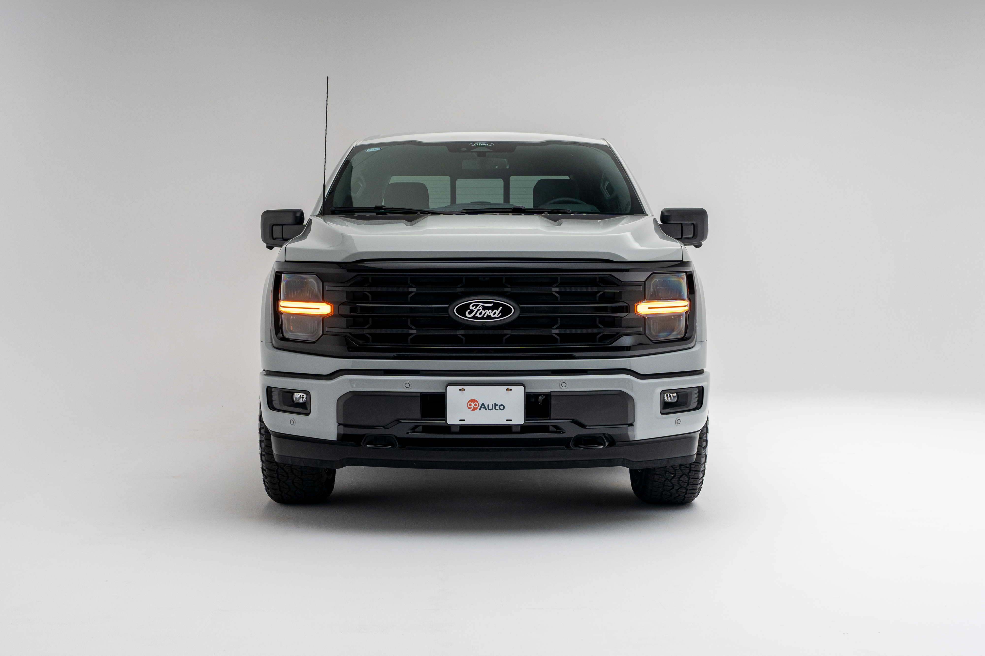 White Ford F-150 pickup truck front view with headlights on