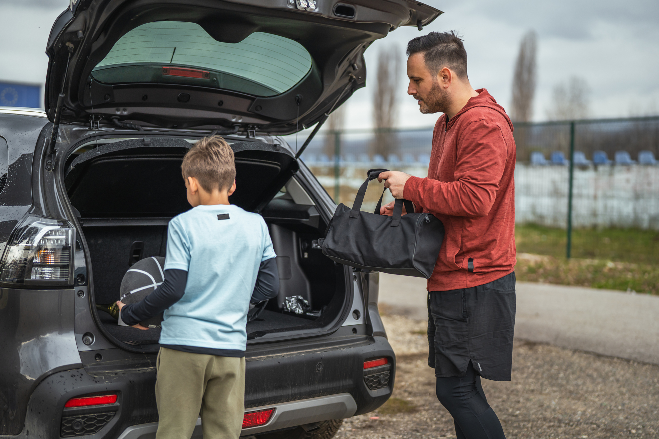 Dad and son getting sports gear from vehicle