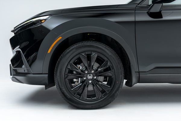 Close-up side view of the front wheel and fender of a black 2026 Honda CR-V, featuring a black multi-spoke alloy wheel.