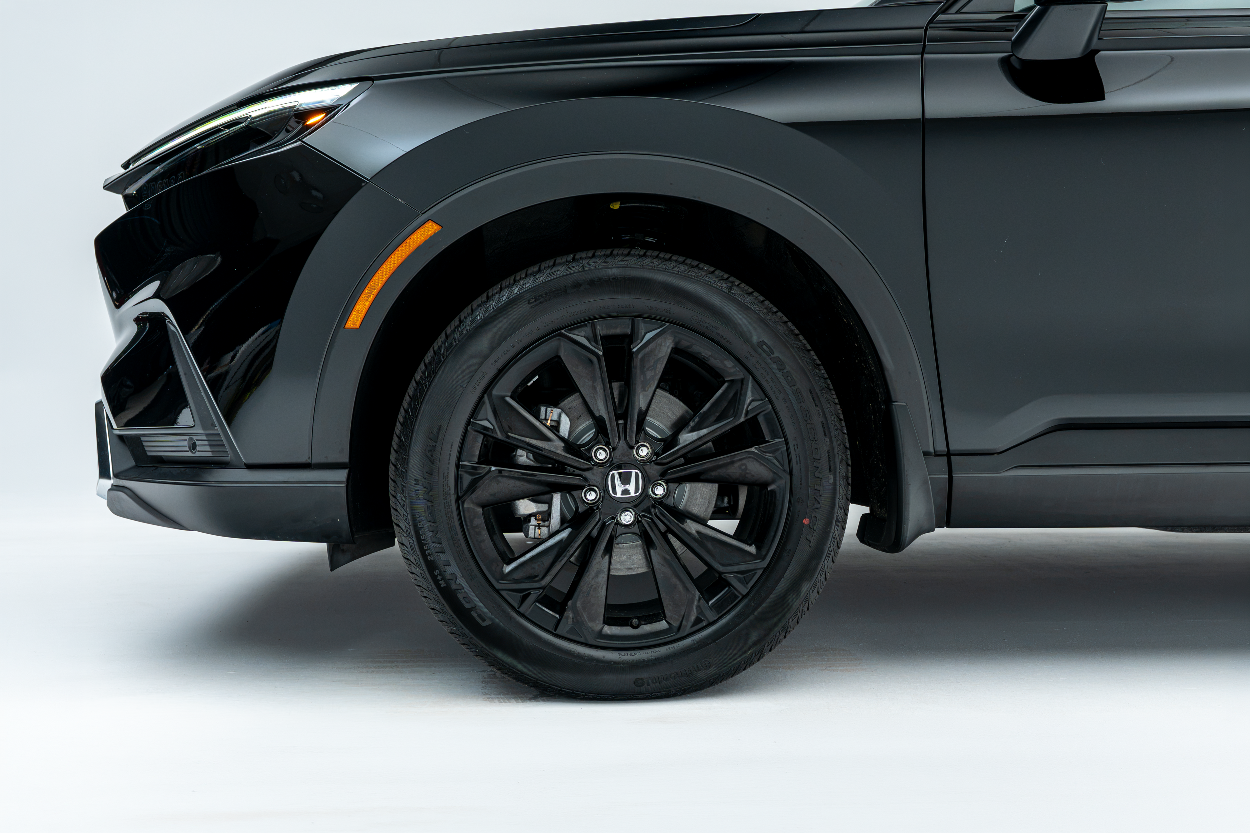 Close-up side view of the front wheel and fender of a black 2026 Honda CR-V, featuring a black multi-spoke alloy wheel.
