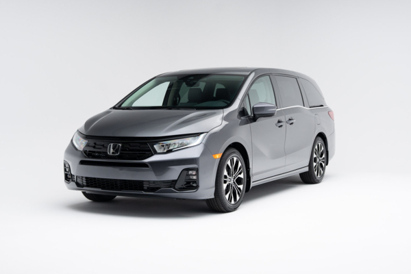 Front three-quarter view of a grey 2026 Honda Odyssey Touring showing LED headlights, grille and alloy wheels.
