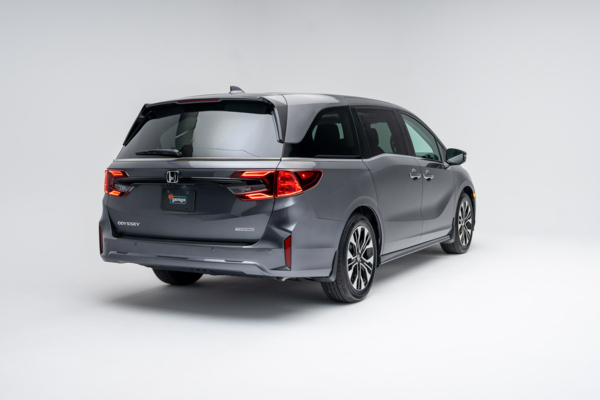 Rear three-quarter view of a grey 2026 Honda Odyssey Touring showing LED taillights, alloy wheels and minivan profile.