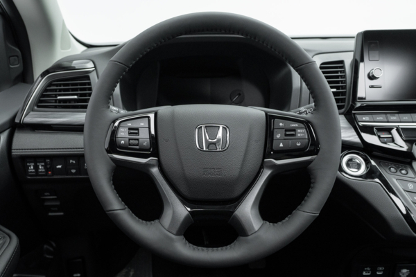 2026 Honda Odyssey Touring steering wheel with driver controls, instrument display and infotainment screen.