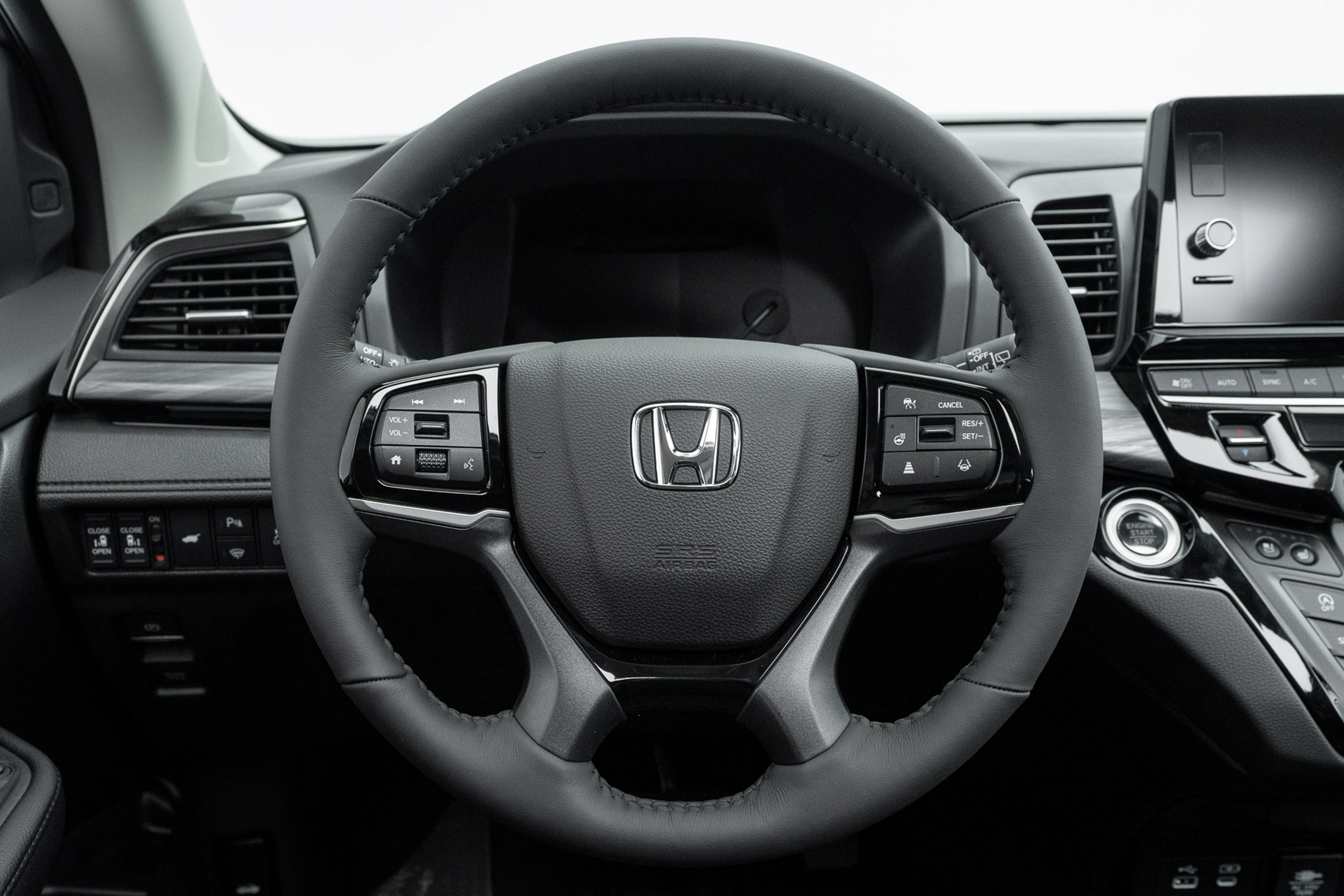 2026 Honda Odyssey Touring steering wheel with driver controls, instrument display and infotainment screen.
