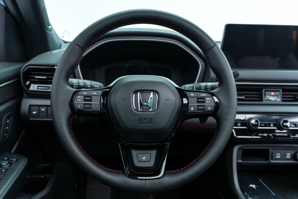 2026 Honda Pilot steering wheel with driver controls, digital instrument display and dashboard.