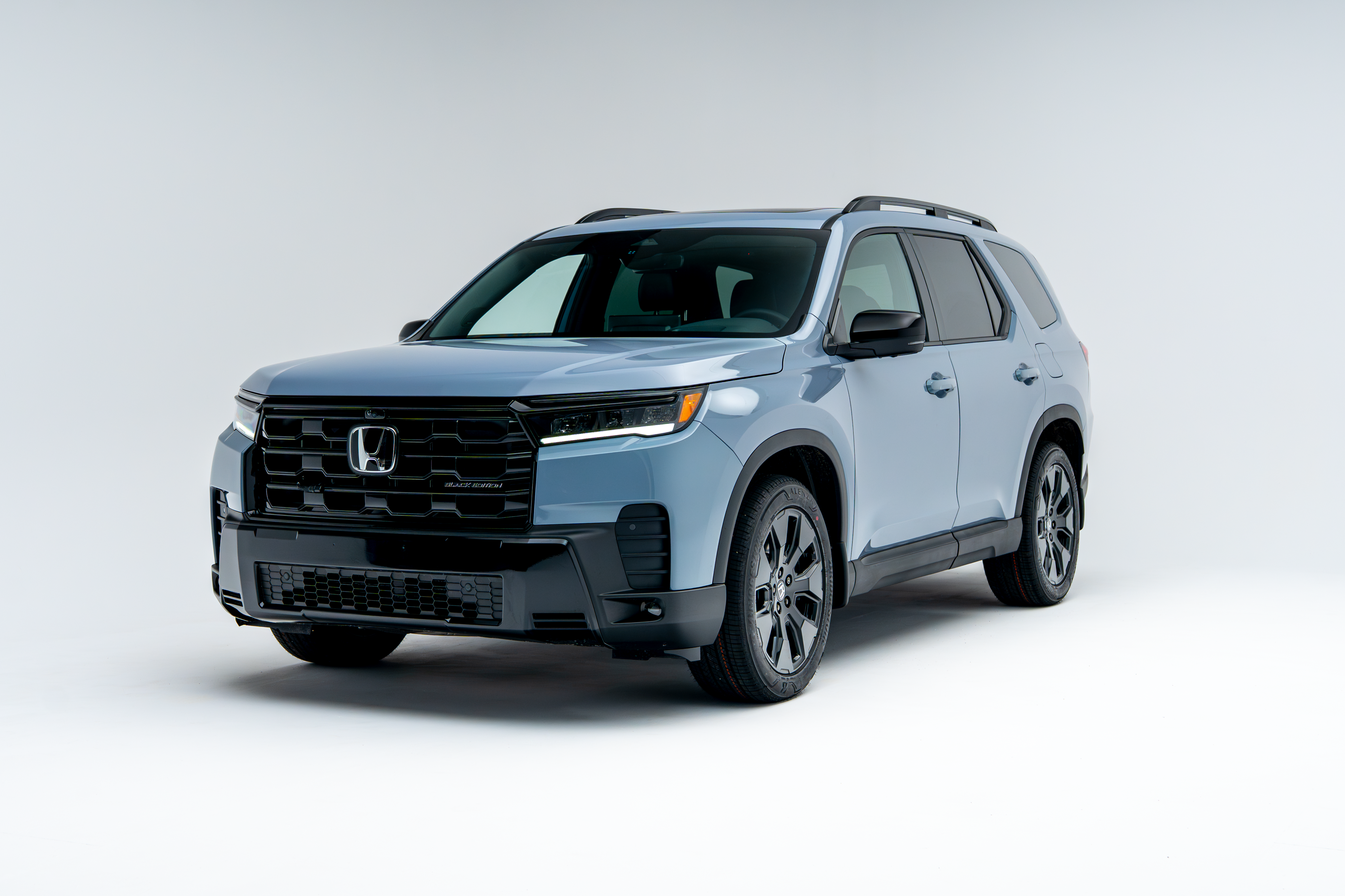 Front three-quarter view of a 2026 Honda Pilot showing LED headlights, grille, alloy wheels and SUV profile.