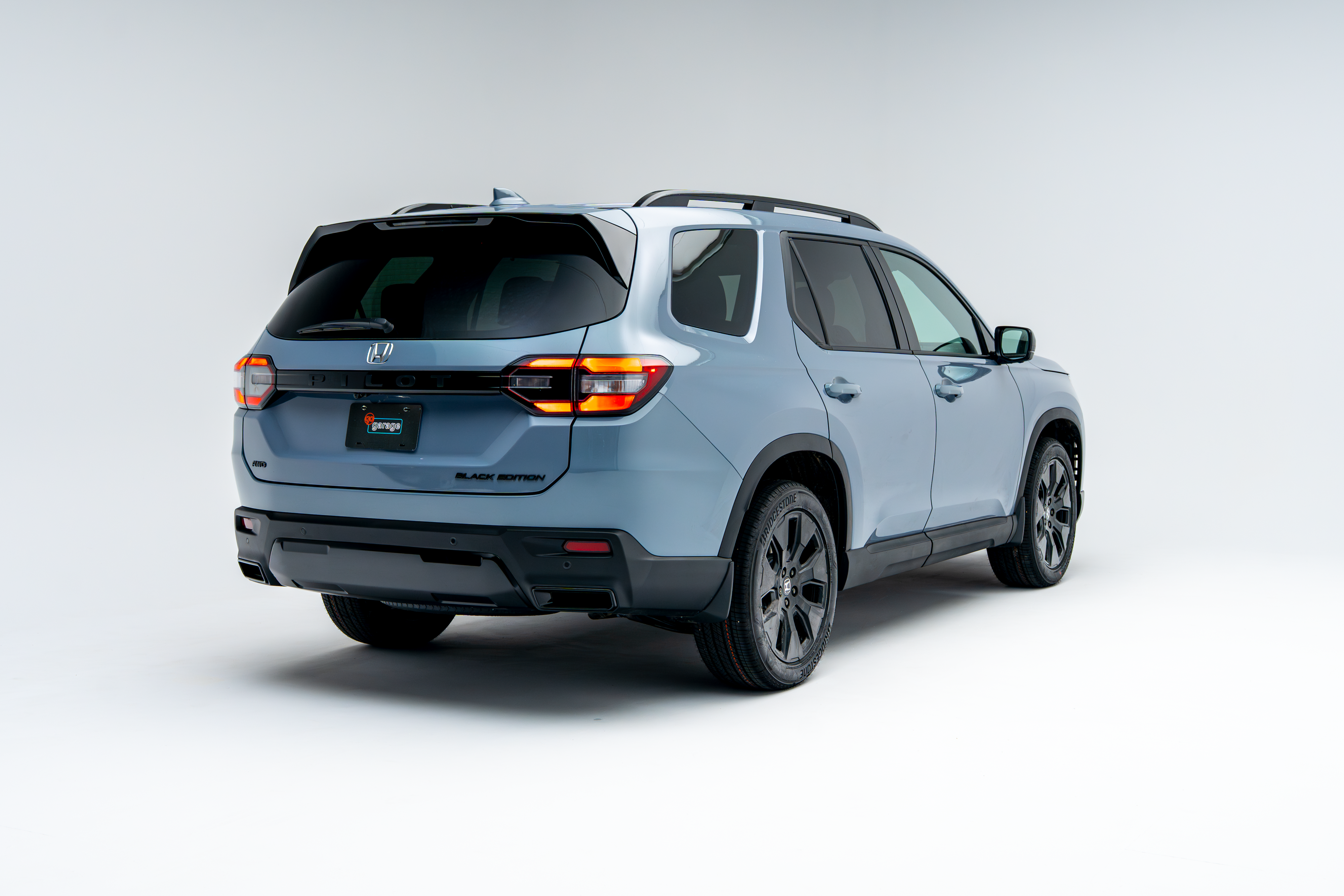 2026 Honda Pilot three-row SUV shown from rear three-quarter angle in light blue
