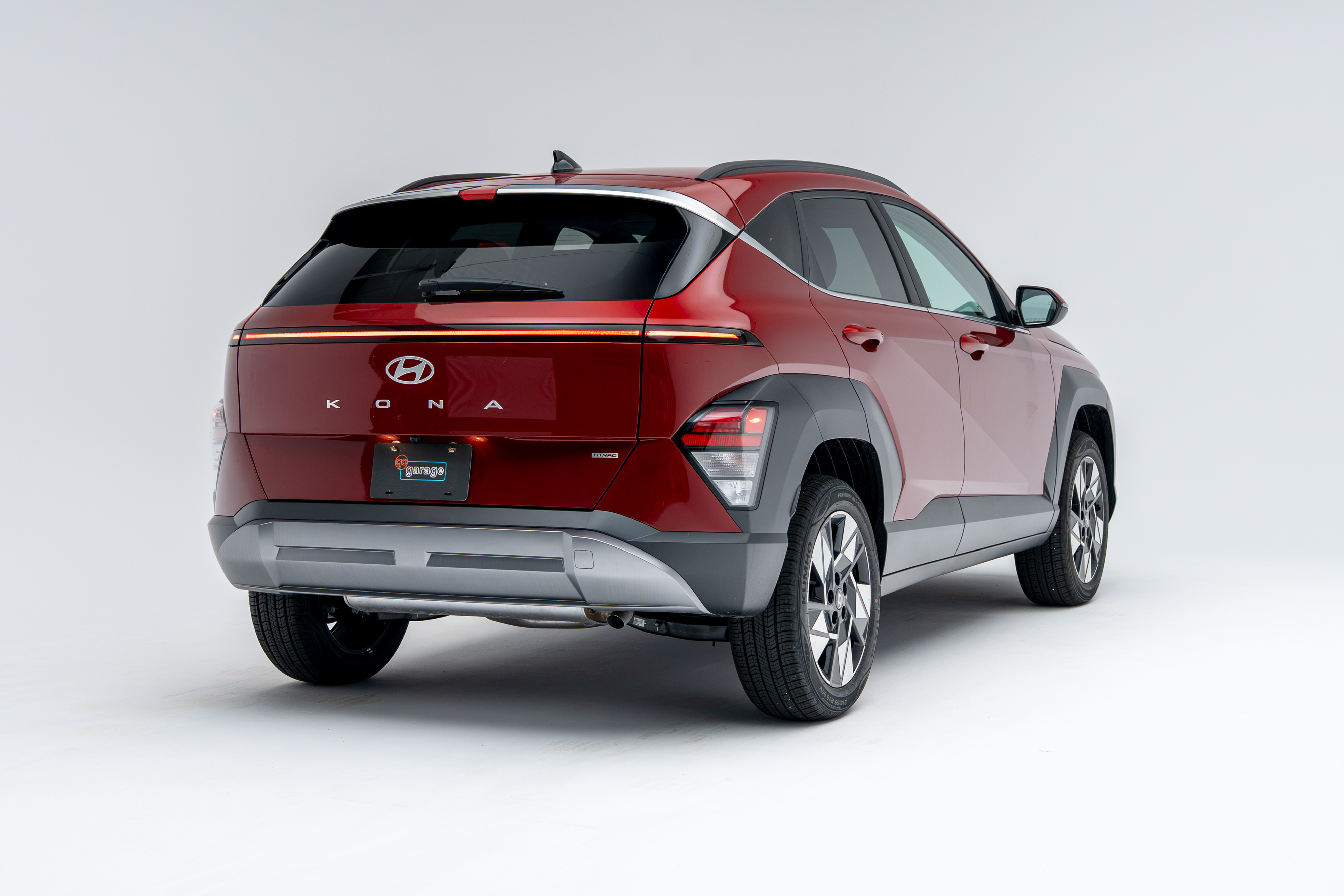 Rear three-quarter view of a red 2026 Hyundai Kona SUV with LED taillights illuminated on a white studio background.