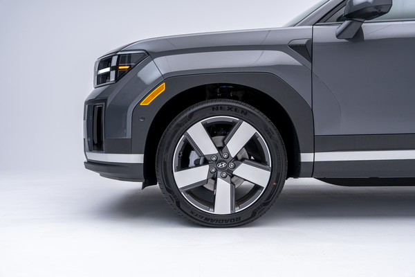 Close-up side view of the front wheel and fender of a grey 2026 Hyundai Santa Fe Hybrid, featuring a two-tone alloy wheel.