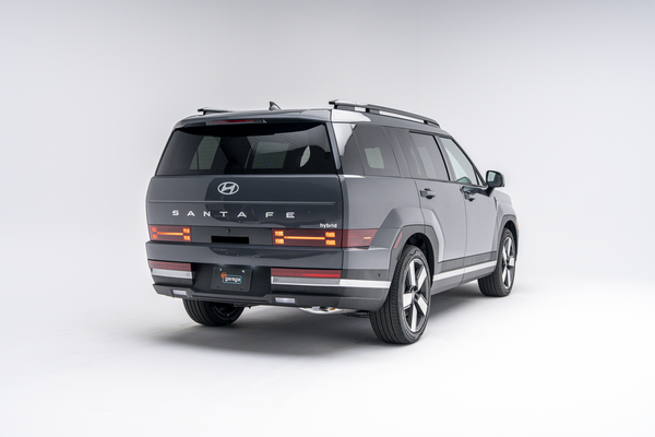 Rear three-quarter view of a grey 2026 Hyundai Santa Fe Hybrid SUV with LED taillights illuminated on a white studio background.