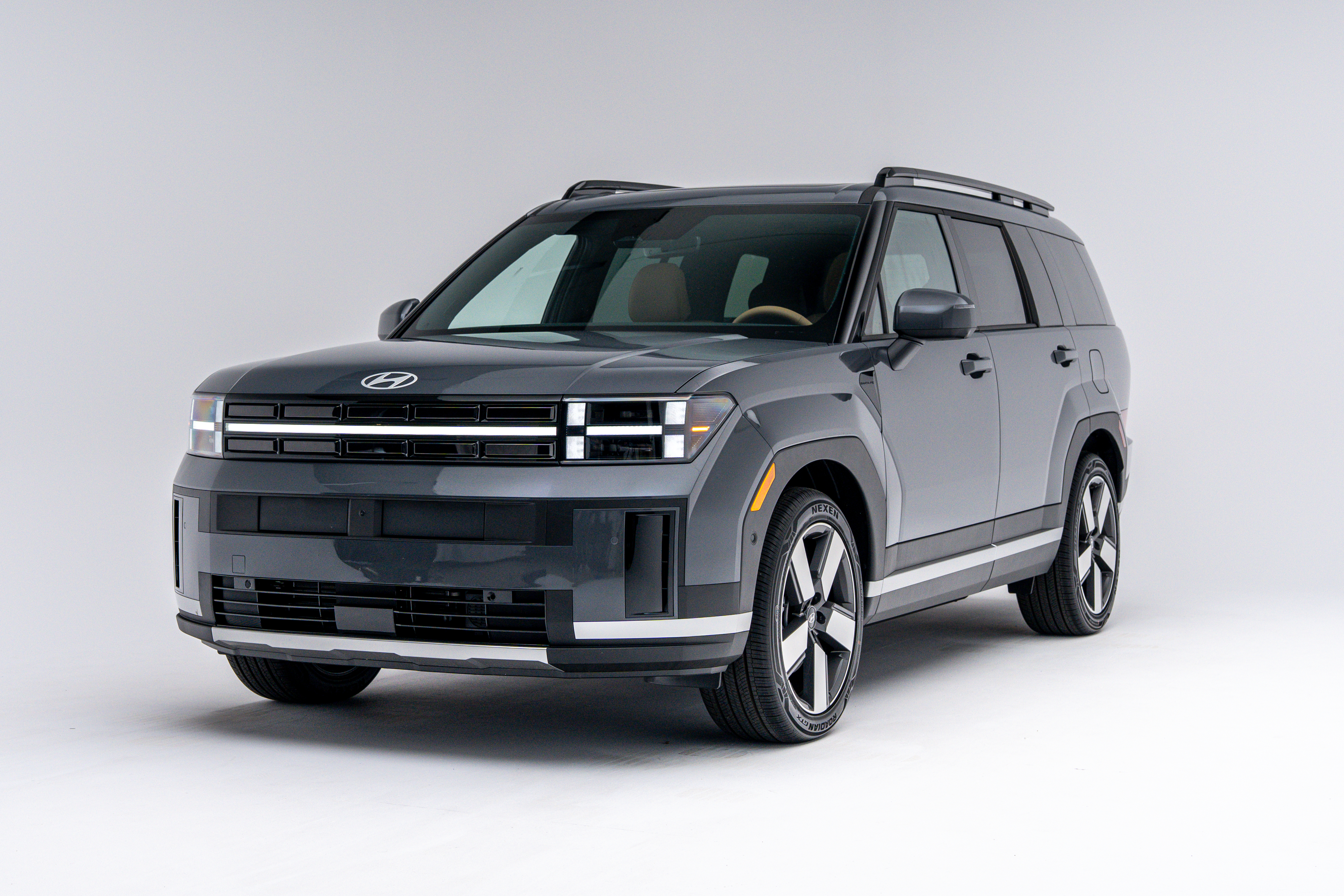 Front three-quarter view of a grey 2026 Hyundai Santa Fe Hybrid SUV on a white studio background.