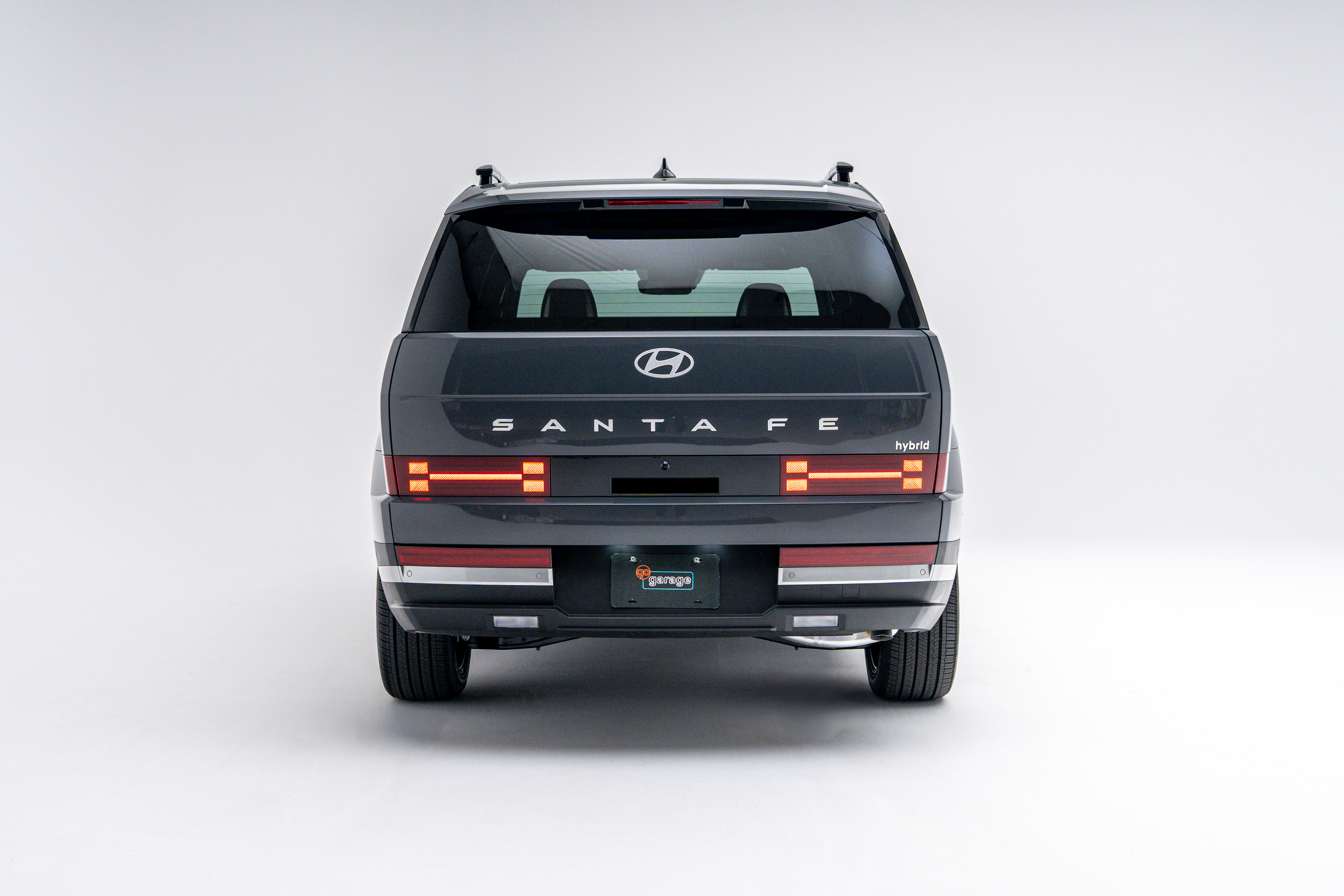 Rear view of a grey 2026 Hyundai Santa Fe Hybrid showing LED taillights, Santa Fe badging and boxy SUV design.