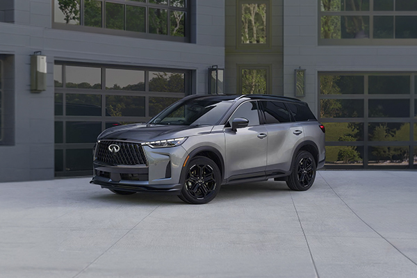 Silver Infiniti QX60 luxury SUV parked in front of modern garage doors