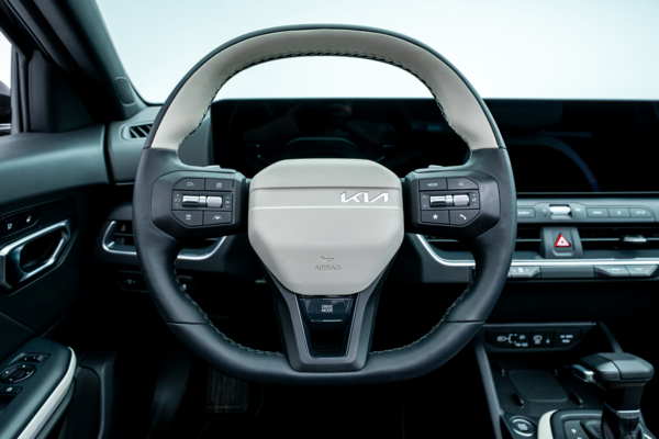 2026 Kia K4 steering wheel with driver controls, digital instrument display and dashboard.