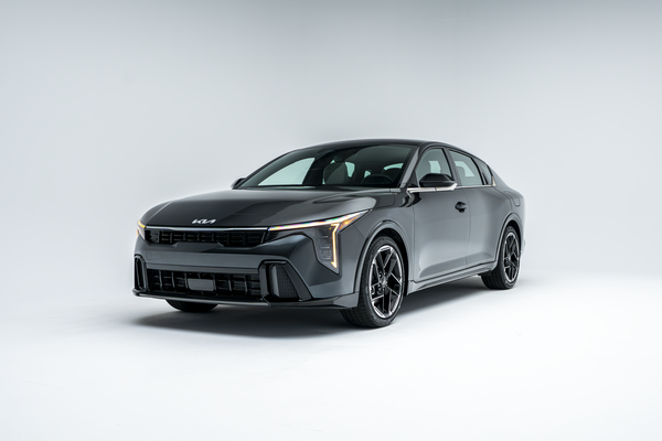 Front three-quarter view of a grey 2026 Kia K4 showing LED headlights, grille, alloy wheels and sedan profile.