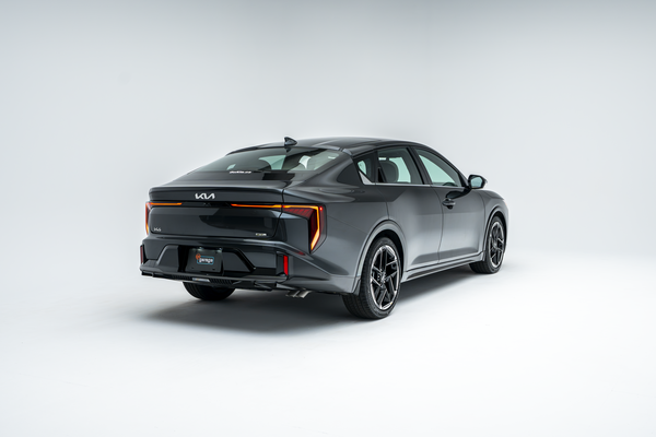 Rear three-quarter view of a grey 2026 Kia K4 showing LED taillights, alloy wheels and sedan profile.