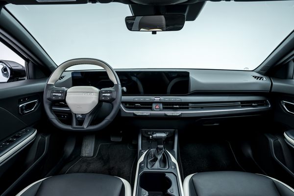 2026 Kia K4 interior dashboard with steering wheel, panoramic digital display, centre console and front seats.