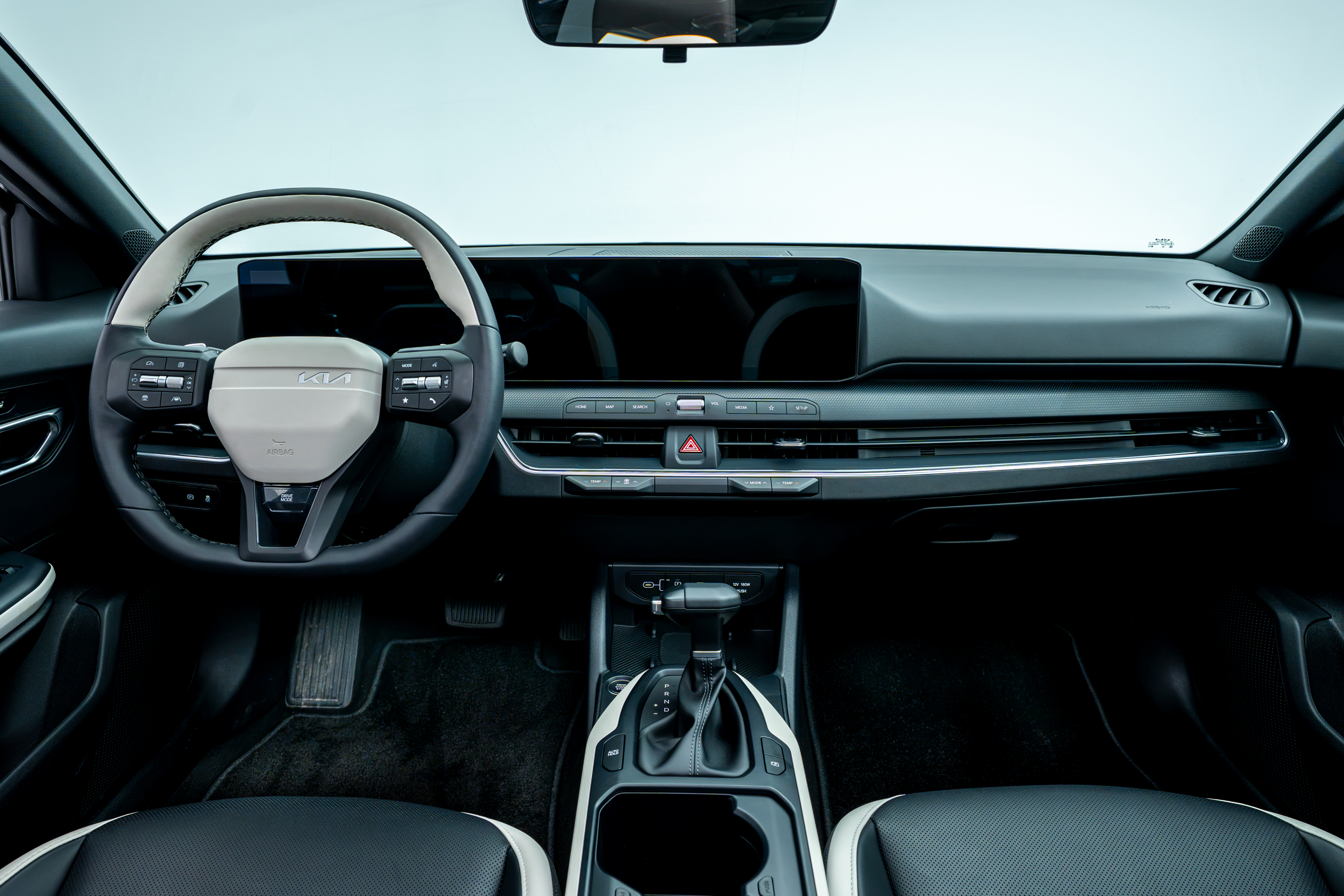 2026 Kia K4 interior dashboard with steering wheel, panoramic digital display, centre console and front seats.