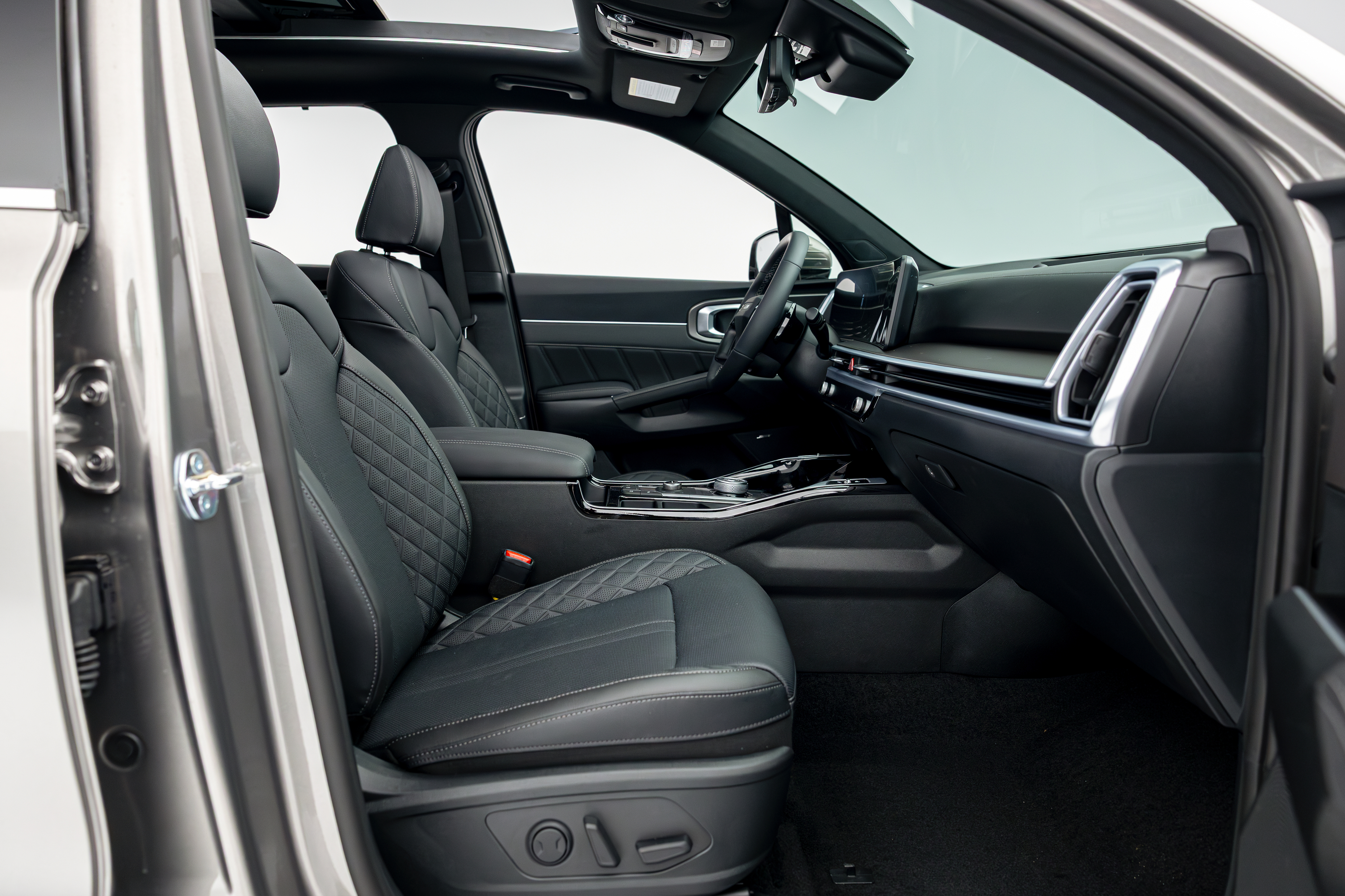2026 Kia Sorento front interior with black seats, dashboard, centre console and panoramic sunroof.