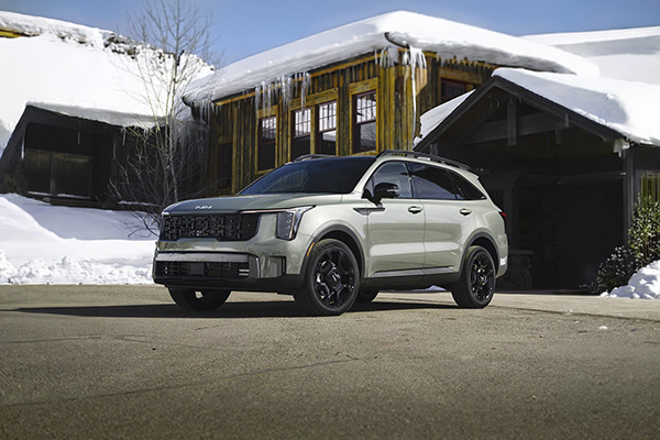 White Kia Sorento parked in driveway with snow-covered buildings in background