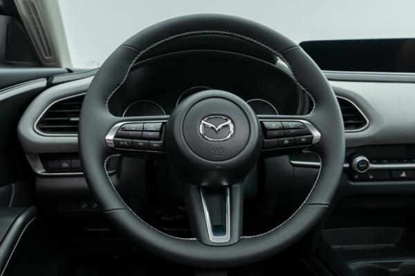 2026 Mazda CX-30 steering wheel with driver controls, instrument cluster and infotainment display.