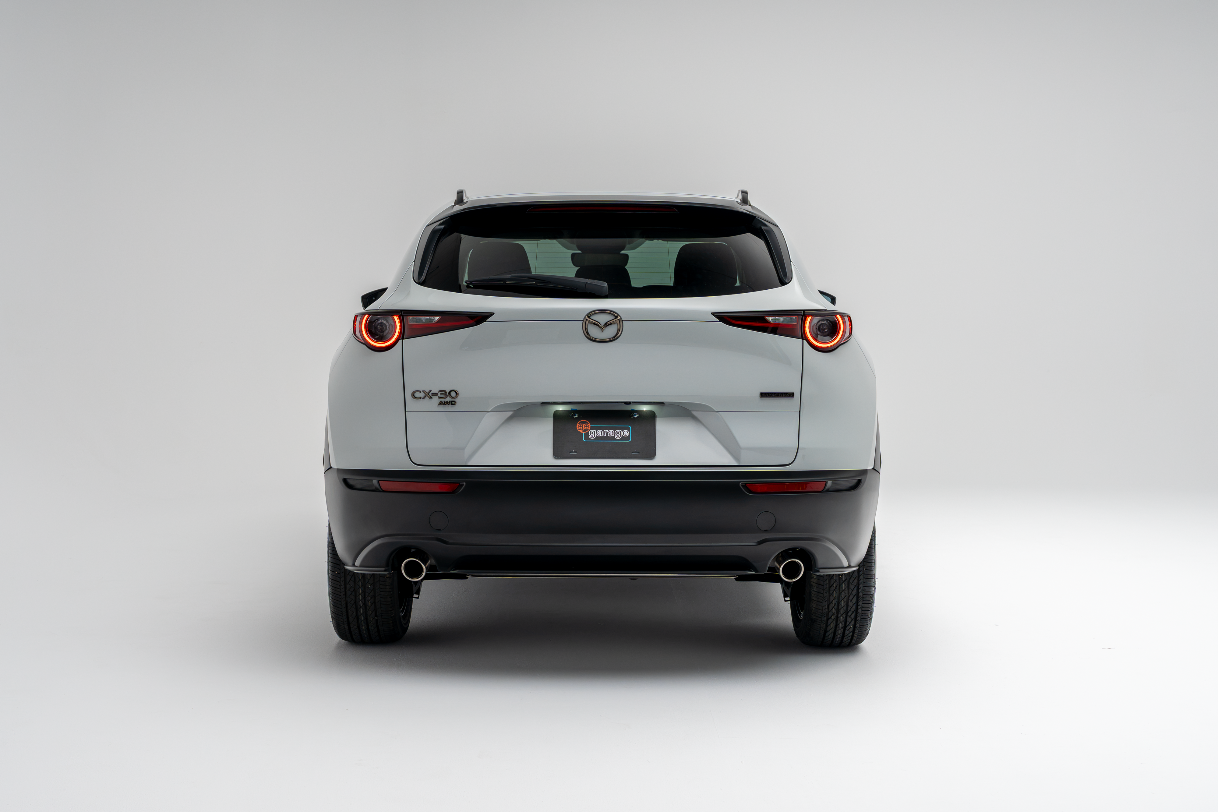 Rear view of a white 2026 Mazda CX-30 showing LED taillights, CX-30 badging and dual exhaust outlets.