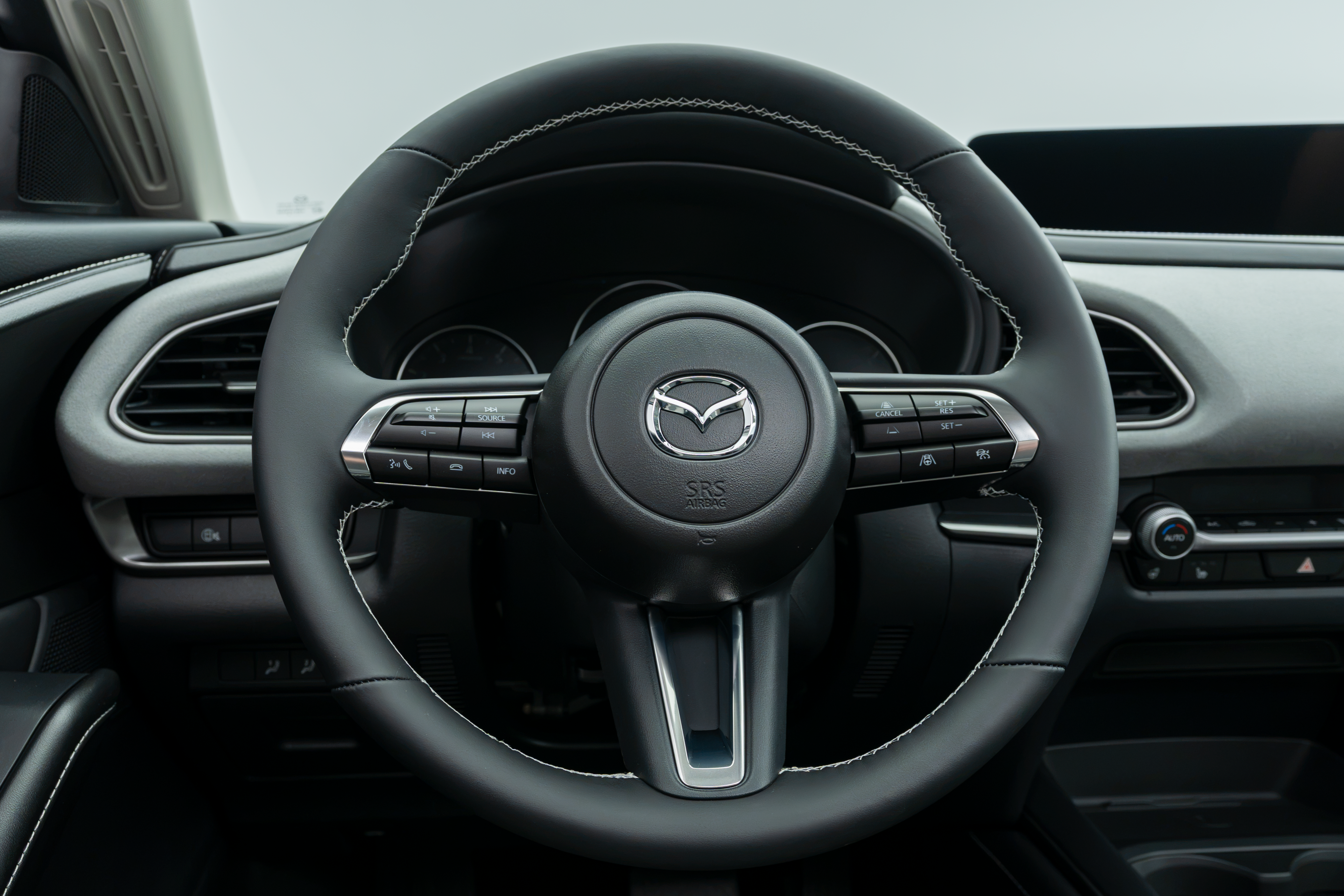 2026 Mazda CX-30 steering wheel with driver controls, instrument cluster and infotainment display.