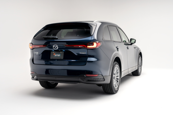 Rear three-quarter view of a blue 2026 Mazda CX-90 showing LED taillights, alloy wheels and SUV profile.