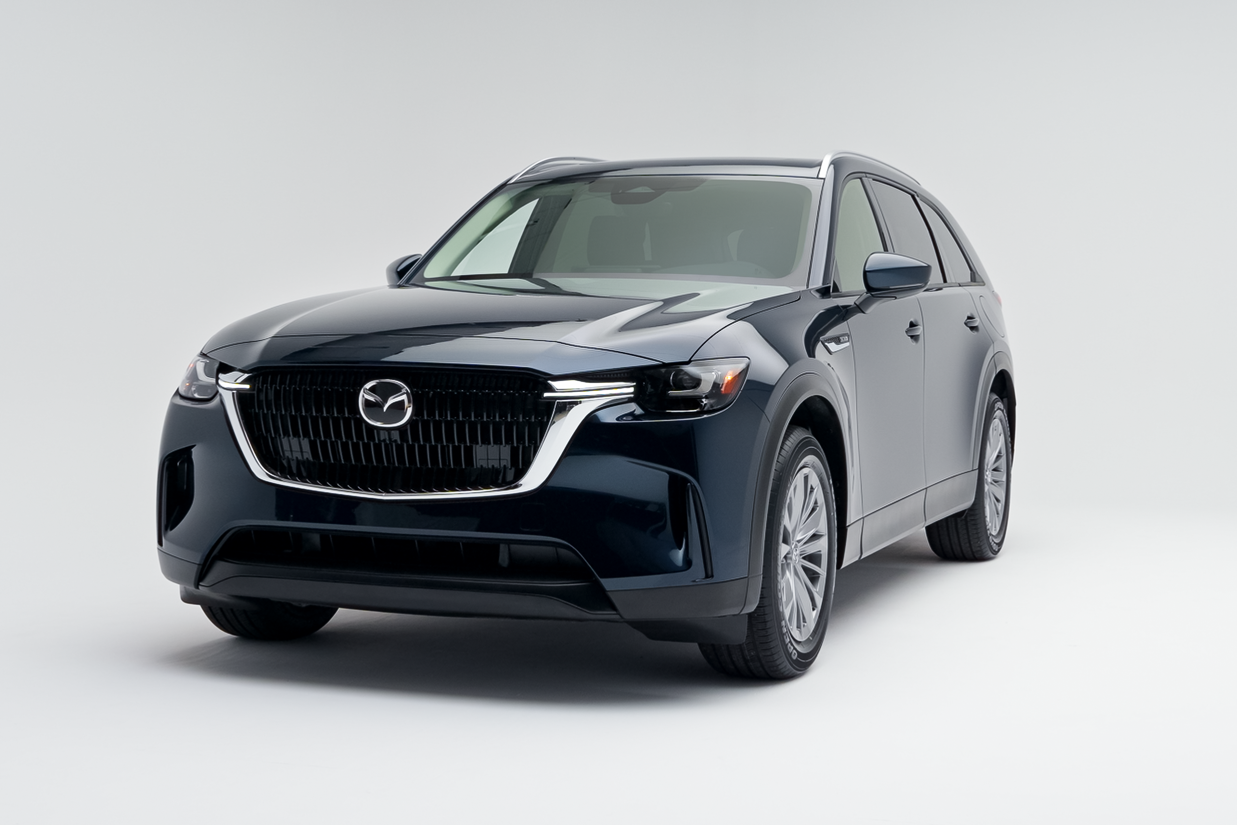 Front three-quarter view of a blue 2026 Mazda CX-90 showing LED headlights, grille, alloy wheels and SUV profile.