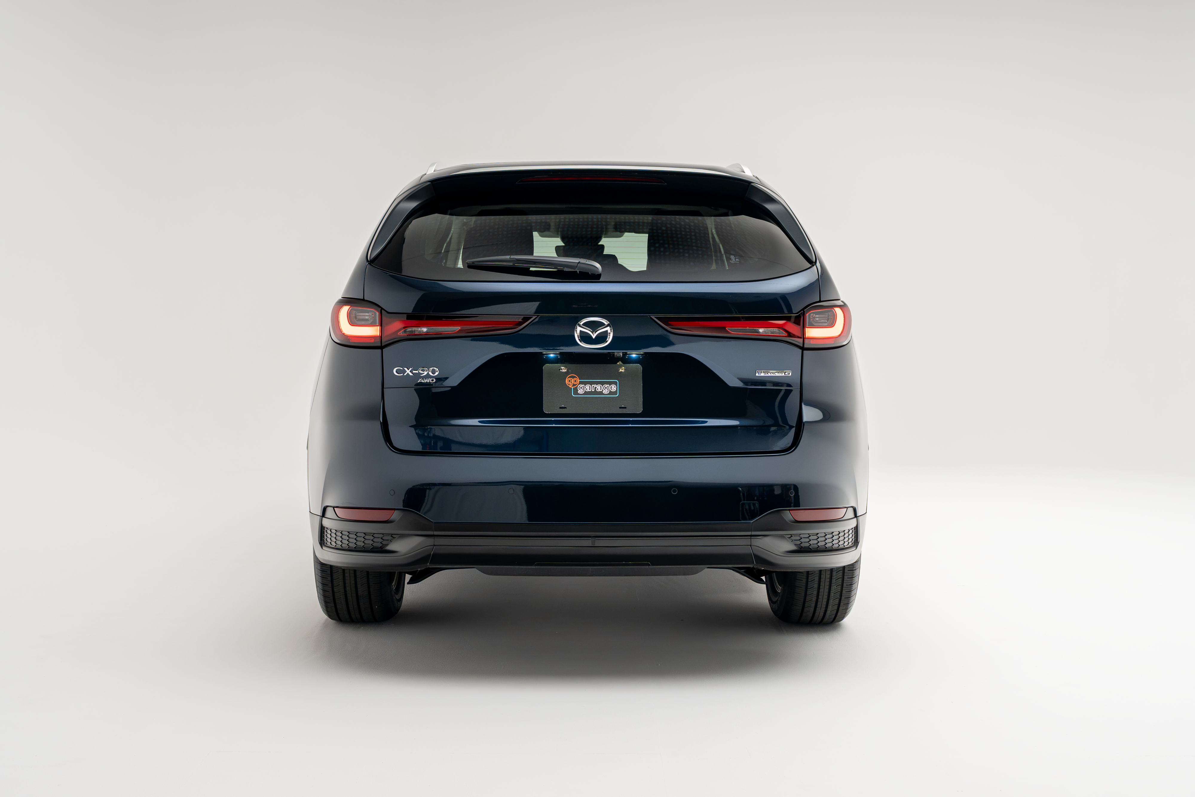 Rear view of a blue 2026 Mazda CX-90 showing LED taillights, CX-90 badging and rear bumper.