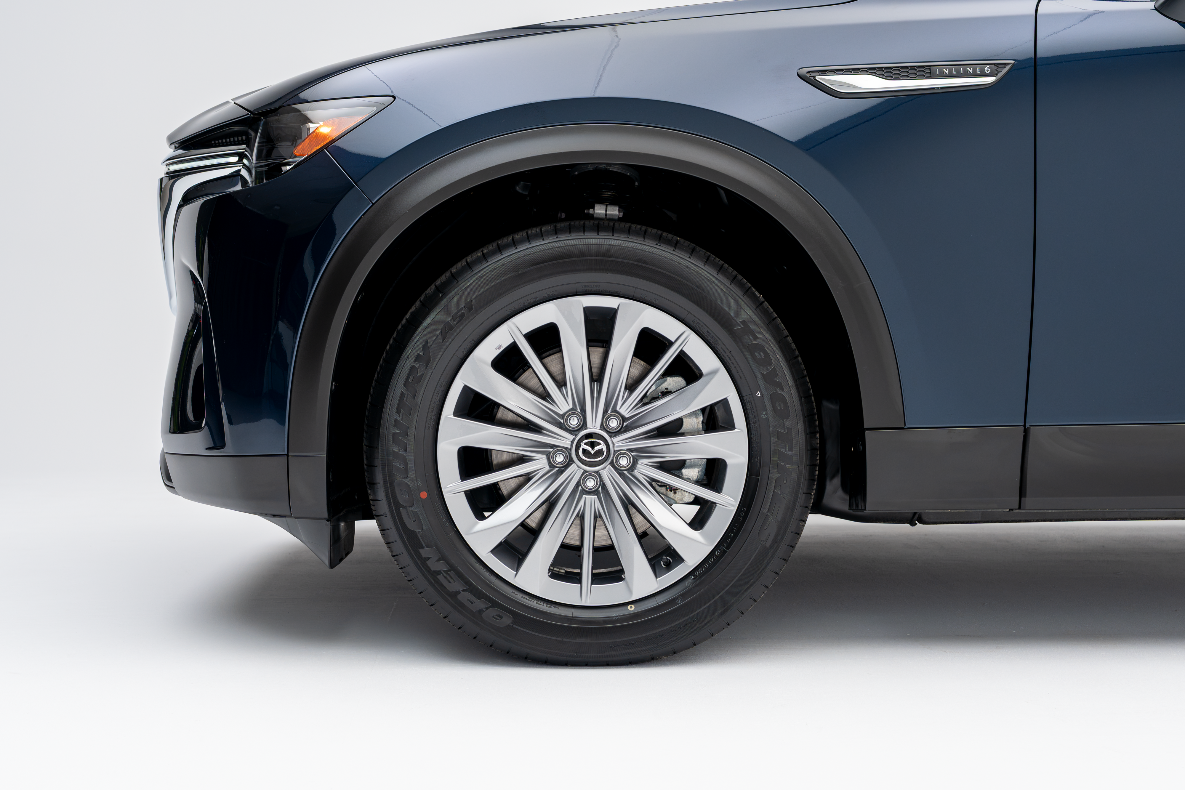 Close-up of a 2026 Mazda CX-90 alloy wheel, tire and front fender.