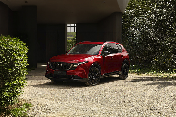 Red Mazda CX-5 parked in modern courtyard with ivy-covered walls