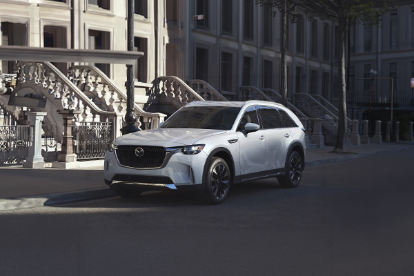 White Mazda CX-90 parked on urban street in front of historic buildings