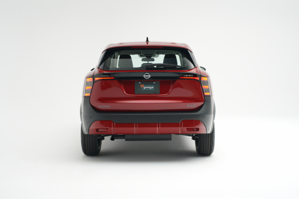 Rear view of a red 2026 Nissan Kicks showing LED taillights, Kicks badging and AWD badging.