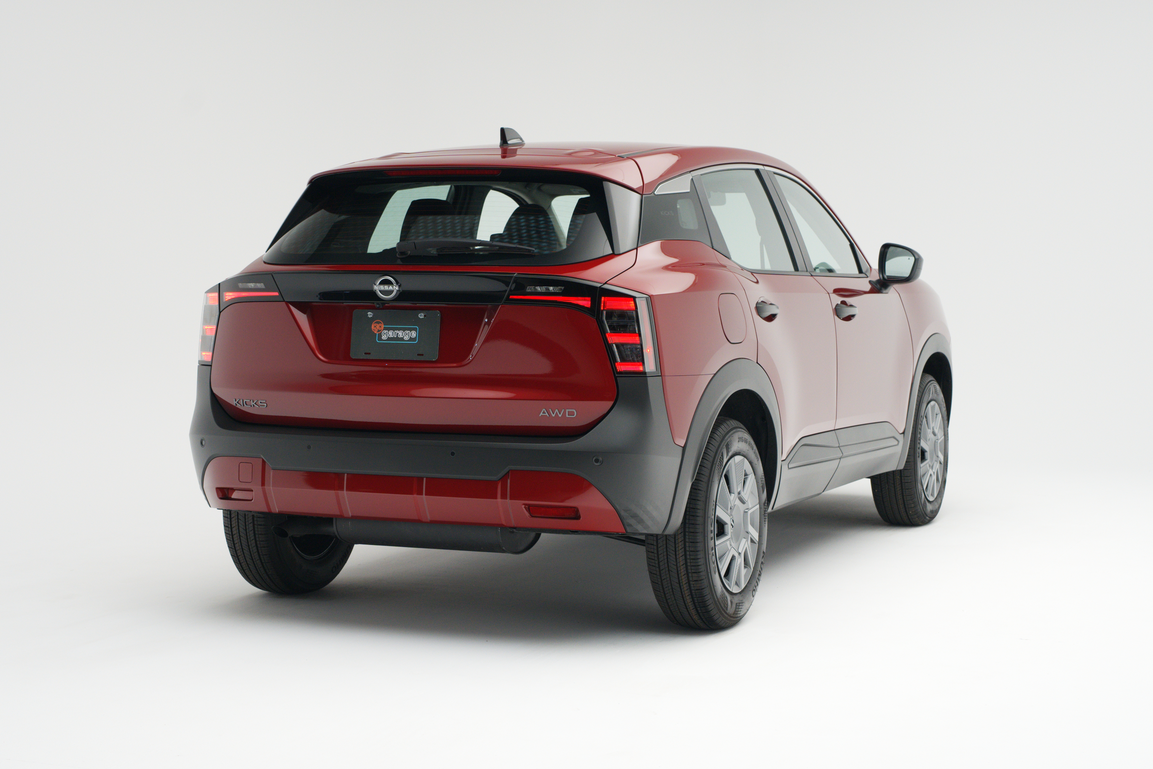 Rear three-quarter view of a red 2026 Nissan Kicks showing LED taillights, alloy wheels and compact SUV profile.