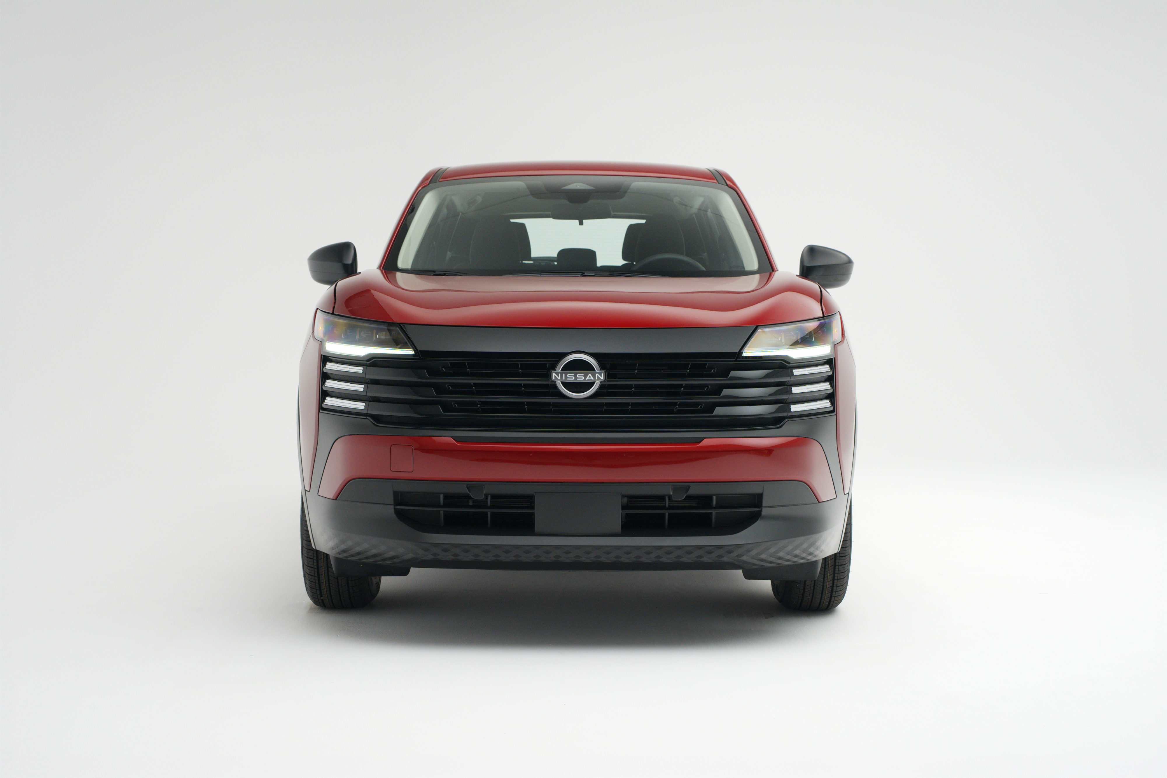 2026 Nissan Kicks in red, shown from a straight-on front view against a white studio background.