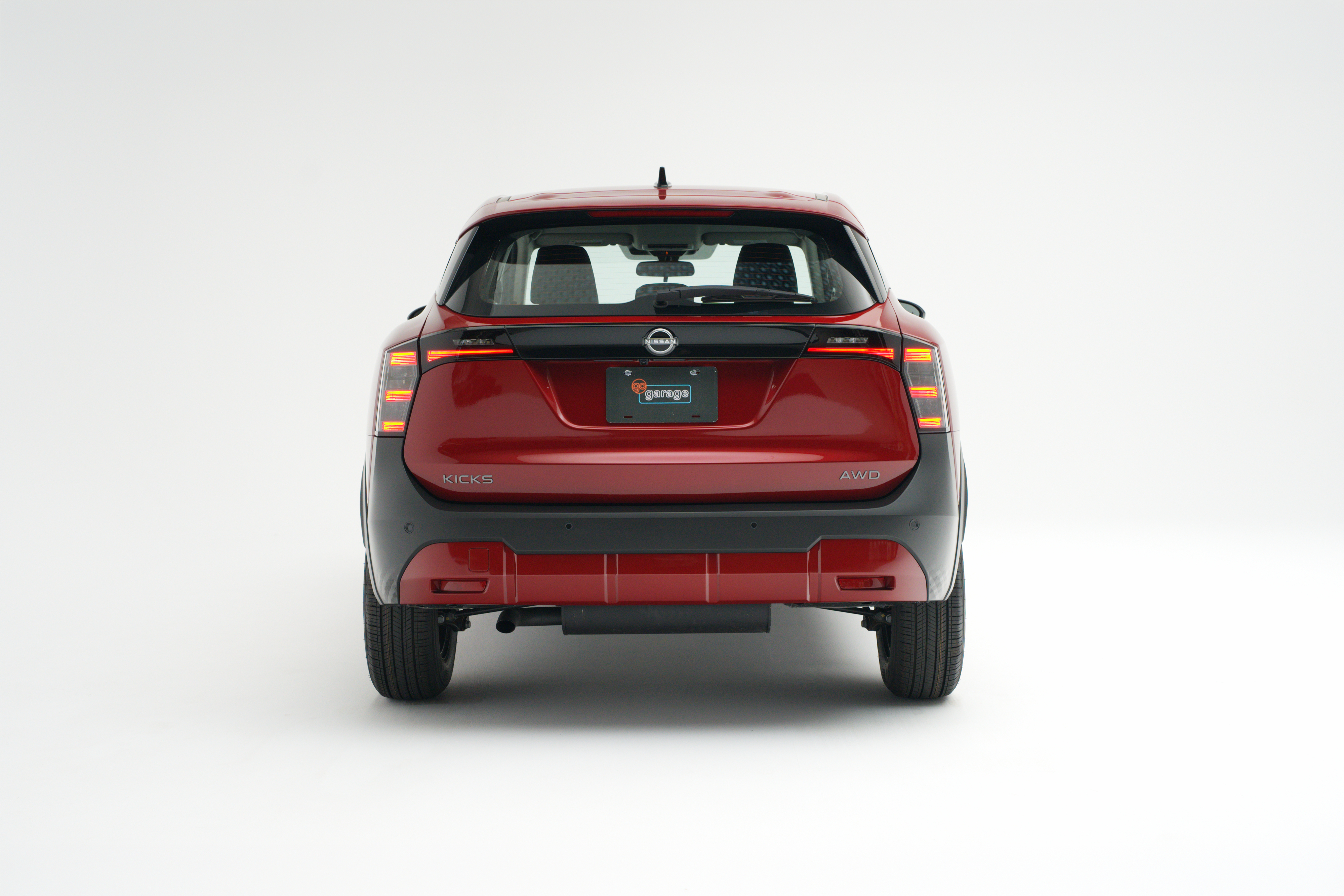 Rear view of a red 2026 Nissan Kicks showing LED taillights, Kicks badging and AWD badging.