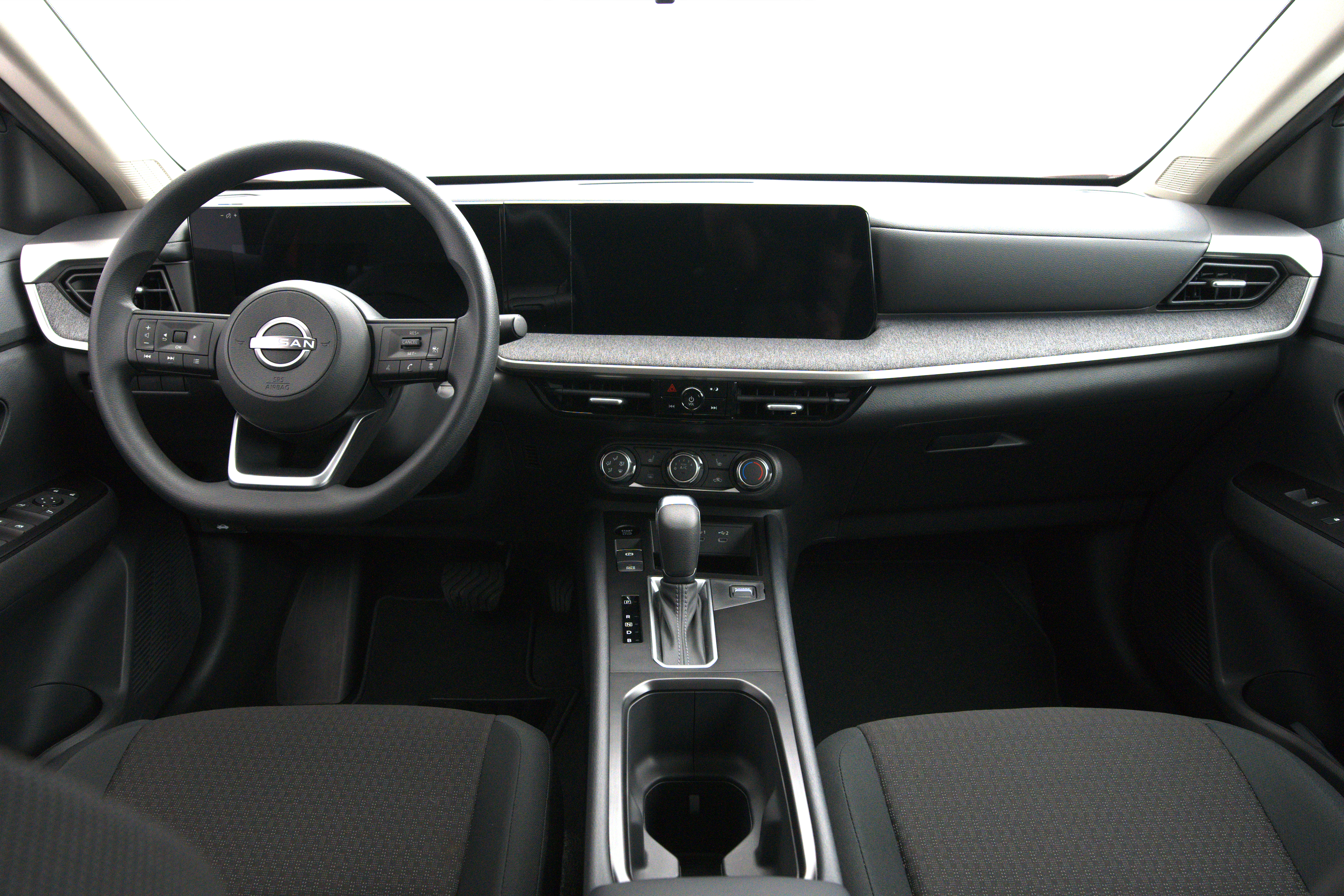 2026 Nissan Kicks interior featuring a black dashboard, steering wheel, digital display, gear shifter and centre console.