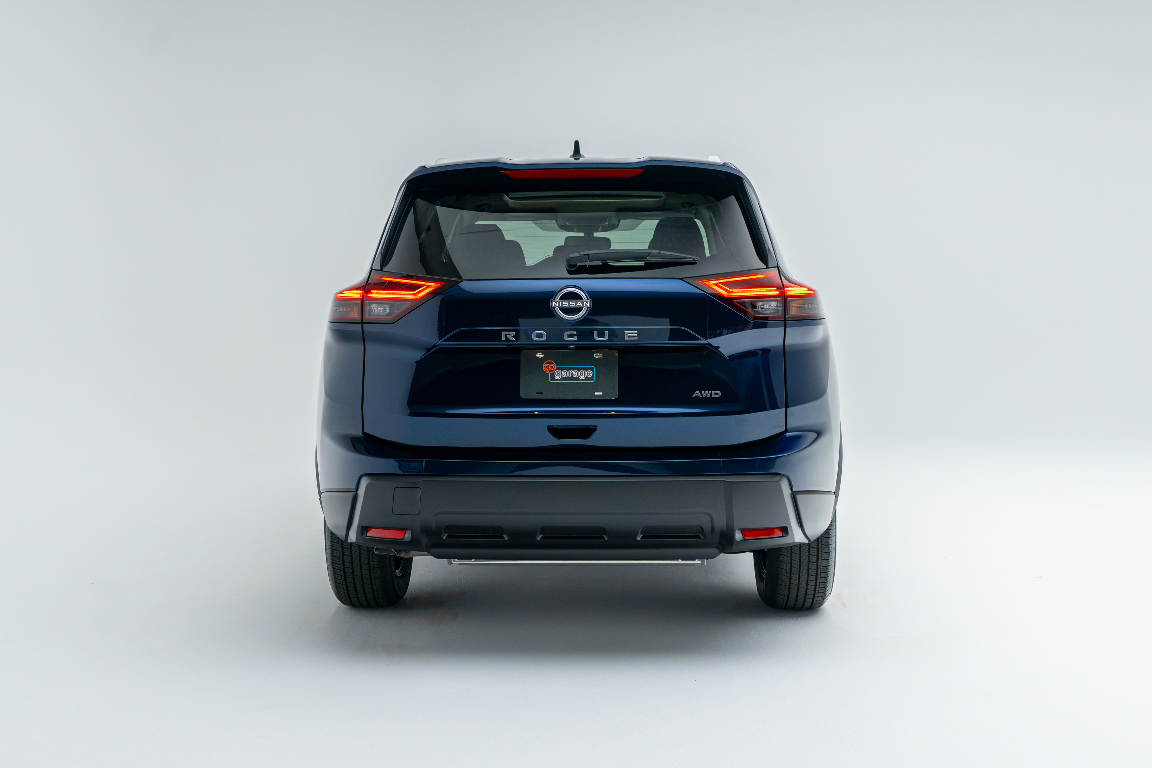 Rear view of a blue Nissan Rogue SV Moonroof showing LED taillights, Rogue badging and AWD badging.